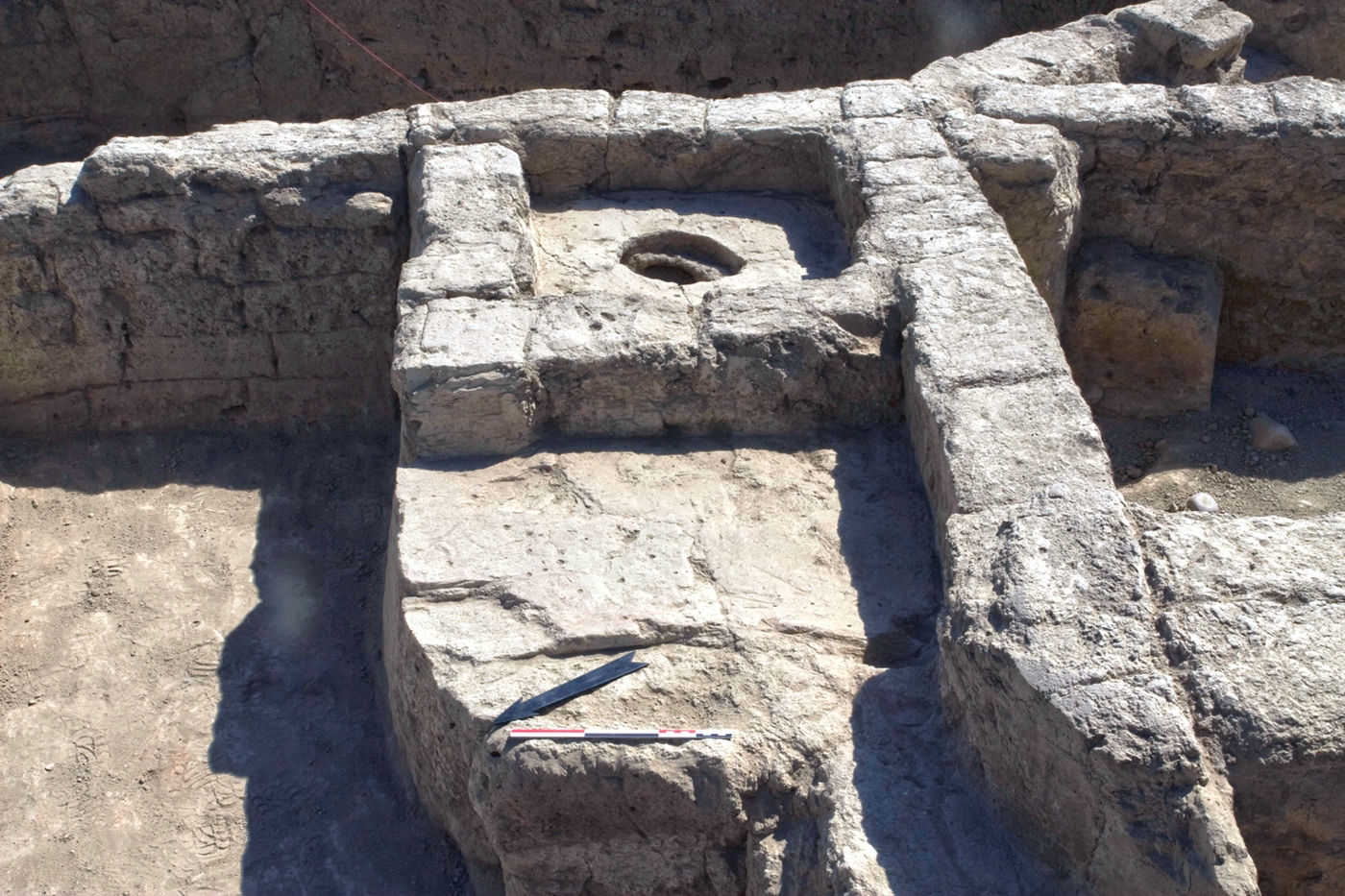 An installation in Building 1 consisting of a podium that was partially hollow and filled with ash and charcoal. A circular opening was, at the time of excavation, closed with a clay stopper. This unusual feature may have been used to store embers.