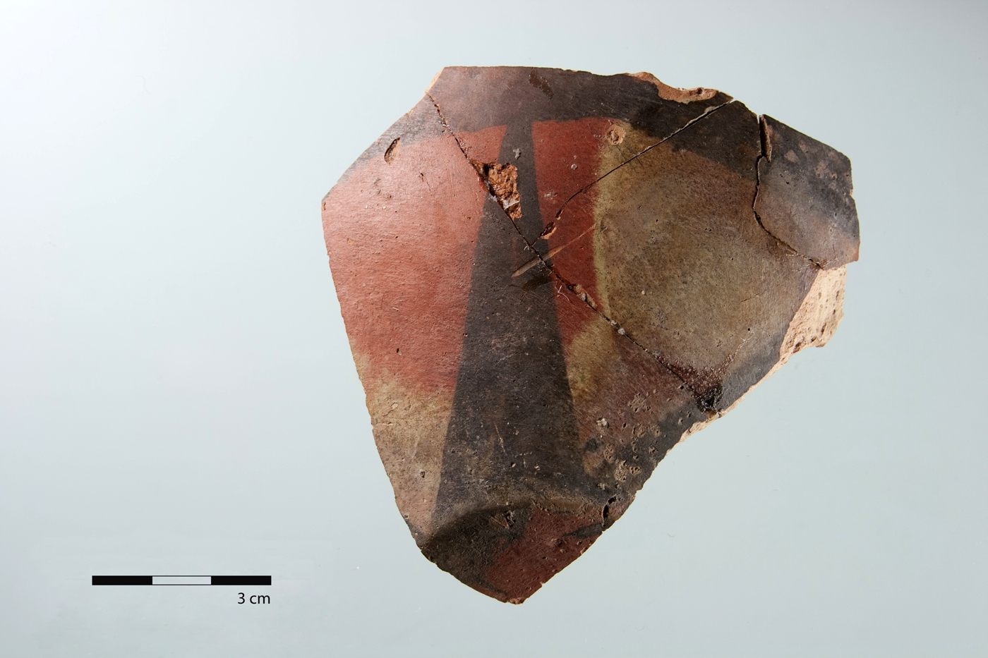 Scherbe eines bemalten Gefäßes der Meana Polytone-Ware mit vom Boden ausgehenden, sich verjüngenden Strahlen, die auf ein am Rand horizontal verlaufendes Band treffen.